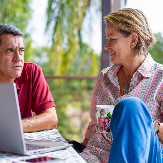 Woman and man at laptop relaxed with a morning coffee