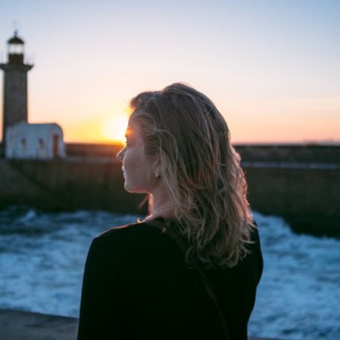 girl back of head looking out to lighthouse