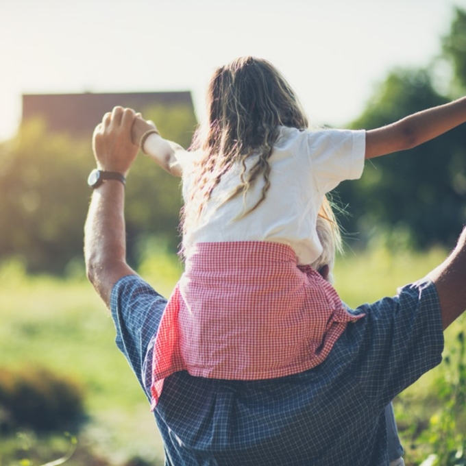father carrying child on shoulders
