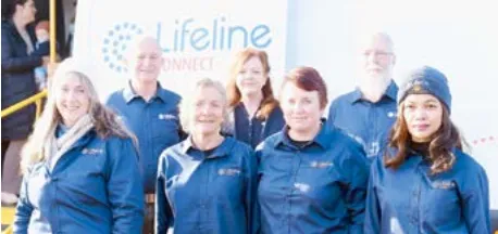 Seven people in blue shirts with a small logo, smiling, standing in front of a white surface with "Lifeline Connect" visible in blue text.